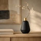 Vase Vienna noir et doré avec branche décorative sur une console contemporaine