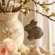 Petit lapin doré suspendu à une branche fleurie dans une décoration printanière