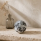 Petite boule Navah blanche et noire présentée sur un anneau-support discret.Suggestion de présentation avec un anneau de rideau 