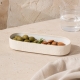  Plat profond Nótos crème avec olives et amandes sur une table lumineuse