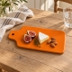  Planche orange avec brie, figue et amandes sur une table en bois clair.