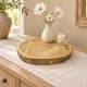 Rondelle en bois brut avec petit vase de fleurs blanches et photophore sur une console.