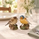 Pinsons Quail sur une table en lin avec vaisselle ivoire, serviette sauge et fleurs blanches.