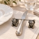 Couteau posé sur le porte-couteau Ange en étain, près d’une assiette blanche sur du linge clair.