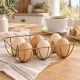 Porte-œufs doré avec six œufs, présenté sur une table de petit-déjeuner en bois clair.