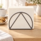 Porte-serviettes en métal gris garni de serviettes ivoire sur une table avec café et biscuits.