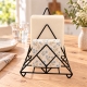 Porte-serviettes noir Madam Stoltz avec serviettes crème et serviettes avec fleurs sur une table en bois clair.