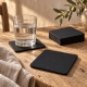 Dessous de verre Black Lizard avec un verre d’eau sur une table en bois, près de lin naturel.