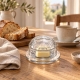 Coupelle à beurre La Rochère en verre transparent, seule sur fond ivoire clair.