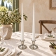 Duo de bougeoirs argentés avec bougies flambeaux rouges sur une nappe damassée ivoire, pour une table élégante