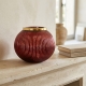 Photophore rouge à rebord doré sur une cheminée en pierre claire dans un intérieur provençal