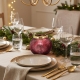 Petit photophore rouge illuminé sur une table de Noël, avec des serviettes bordeaux et un sapin lumineux en arrière-plan.