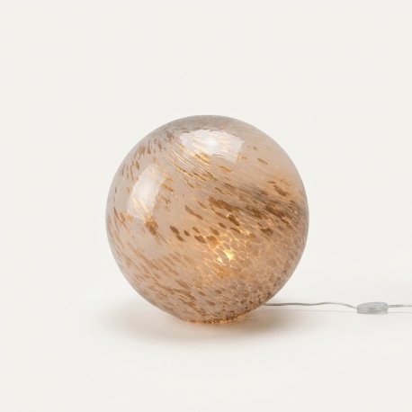 Lampe boule en verre blanc et doré avec câble transparent sur fond clair.